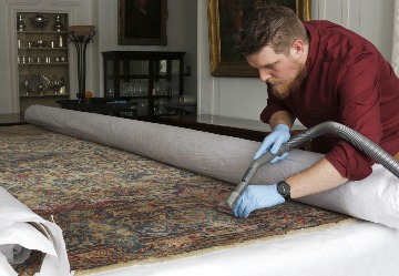 Staff member cleans a rug