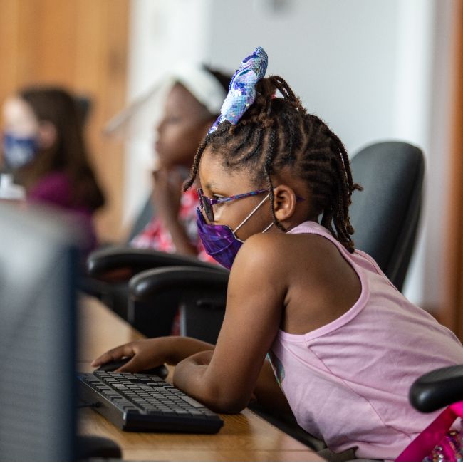 Child working in computer lab with face mask on
