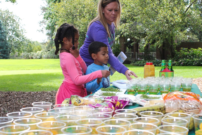 An adult and two children examine items on a table