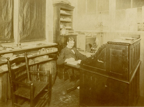 C.S. Mott sits at a desk in his office, circa 1902
