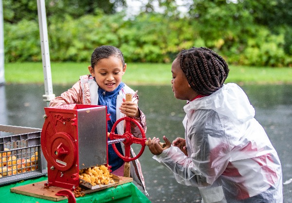 Two children use the cider press