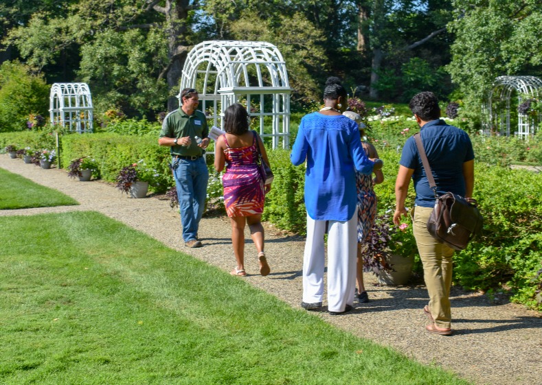 A group takes a walking garden tour through the rose garden