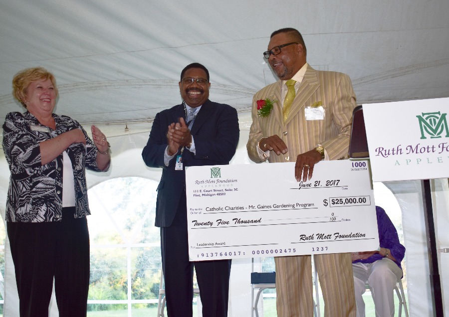 Greg Gaines holds a giant check for $25,000 after winning the Ruth Mott Foundation Leadership Award