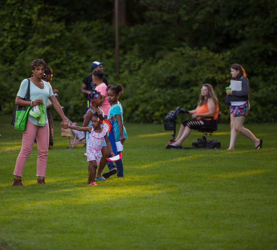 Guests, including one using a motorized wheelchair, attend an event on the lawn