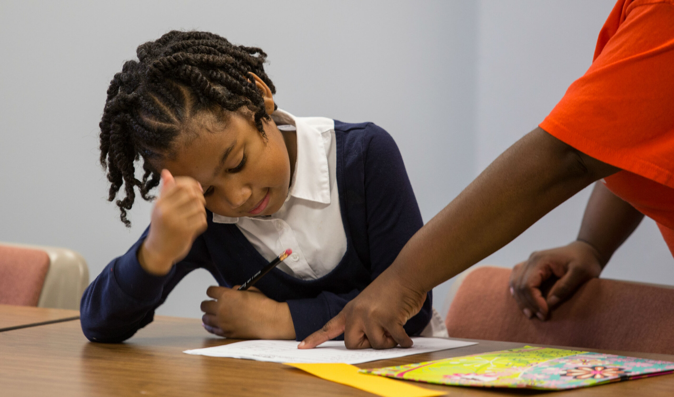 A teacher helping a young girl with her homework.