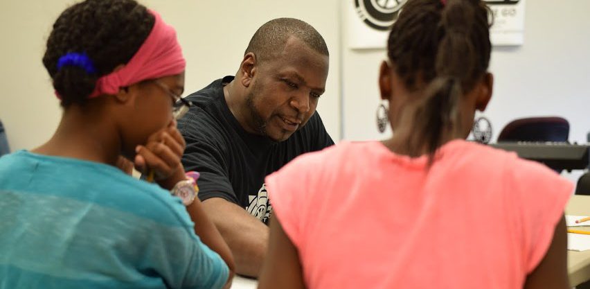 Three people talking inside the Flint Public Library