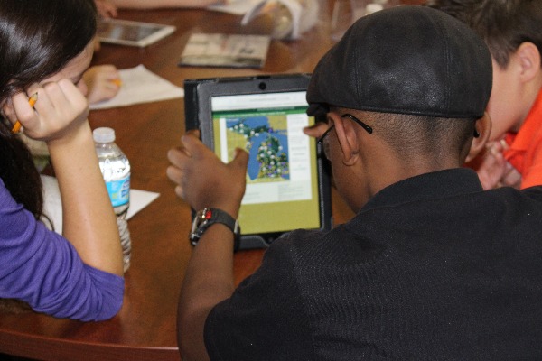 Youth on a field trip at Applewood look at a tablet with a map of Michigan