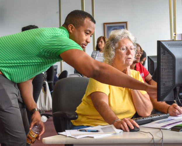 A man assists a woman at a computer during a dashboard workshop