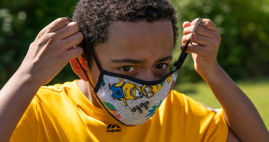 A young boy puts on a face mask