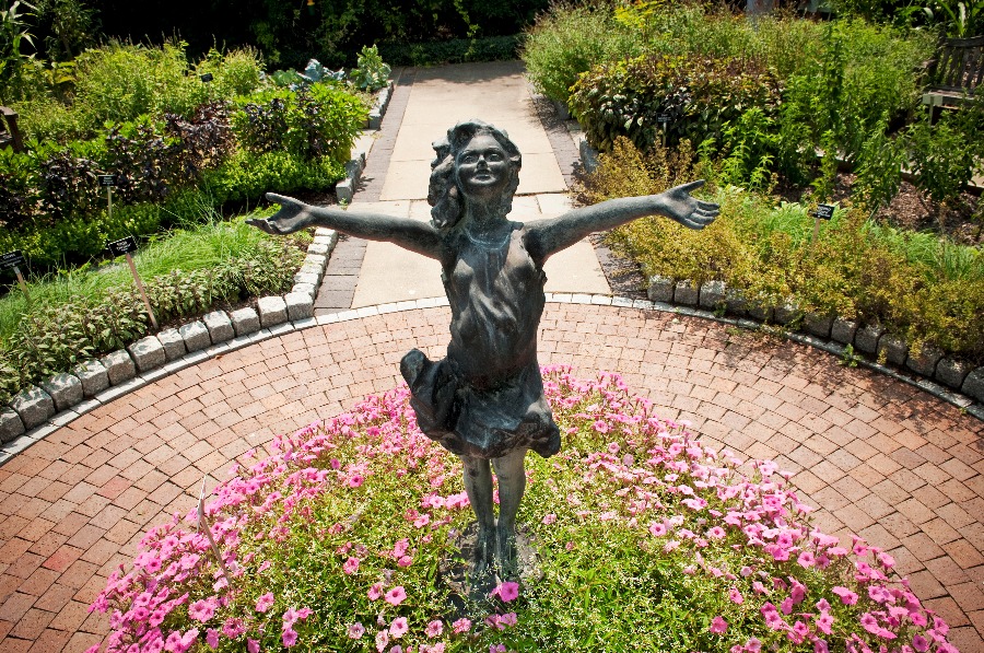 A statue of a girl with her arms outstretched is pictured in the Demonstration Garden at Applewood