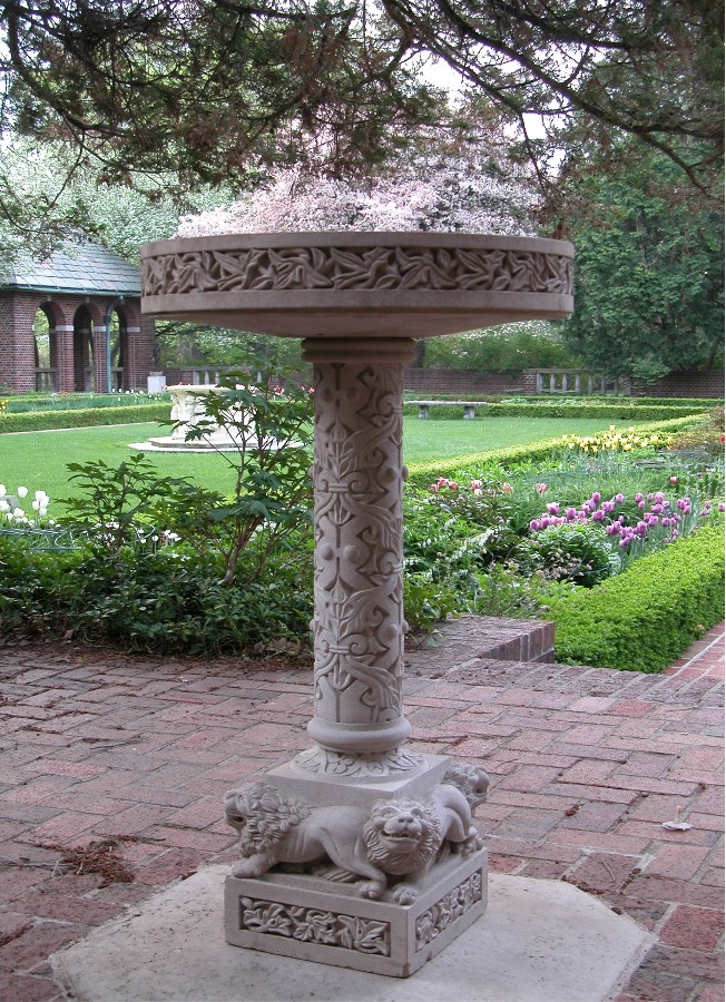 An intricately carved stone birdbath is pictured in the perennial garden at Applewood