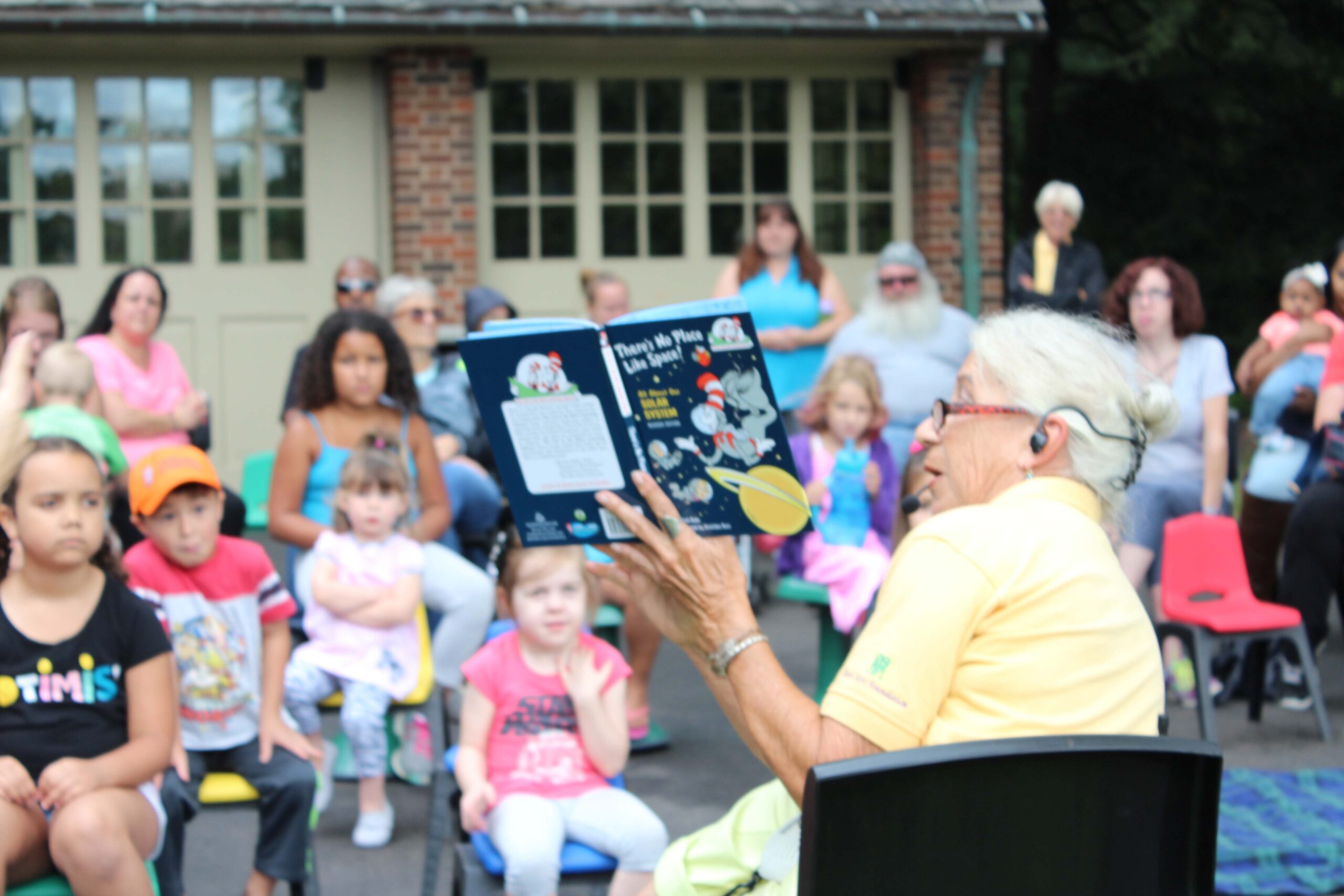 https://www.ruthmottfoundation.org/wp-content/uploads/2021/06/a-woman-reading-a-dr-seuss-book-at-storytime-at-applewood-scaled.jpg