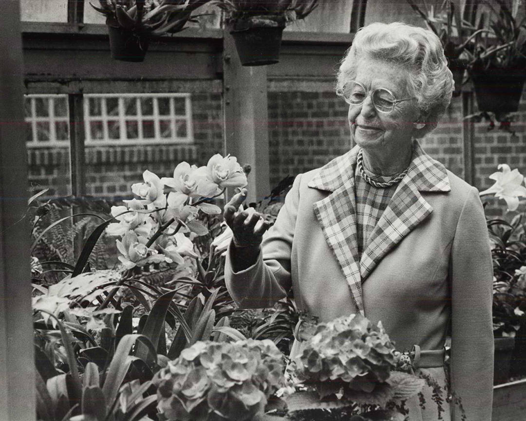 Ruth Mott admires flowers inside the greenhouse