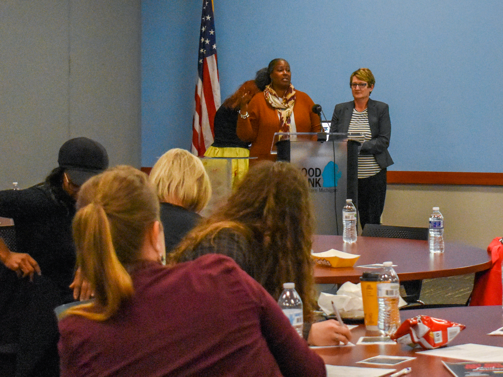 Two women standing in front of a group of people discussing the importance of getting involved in the census and redistricting efforts.