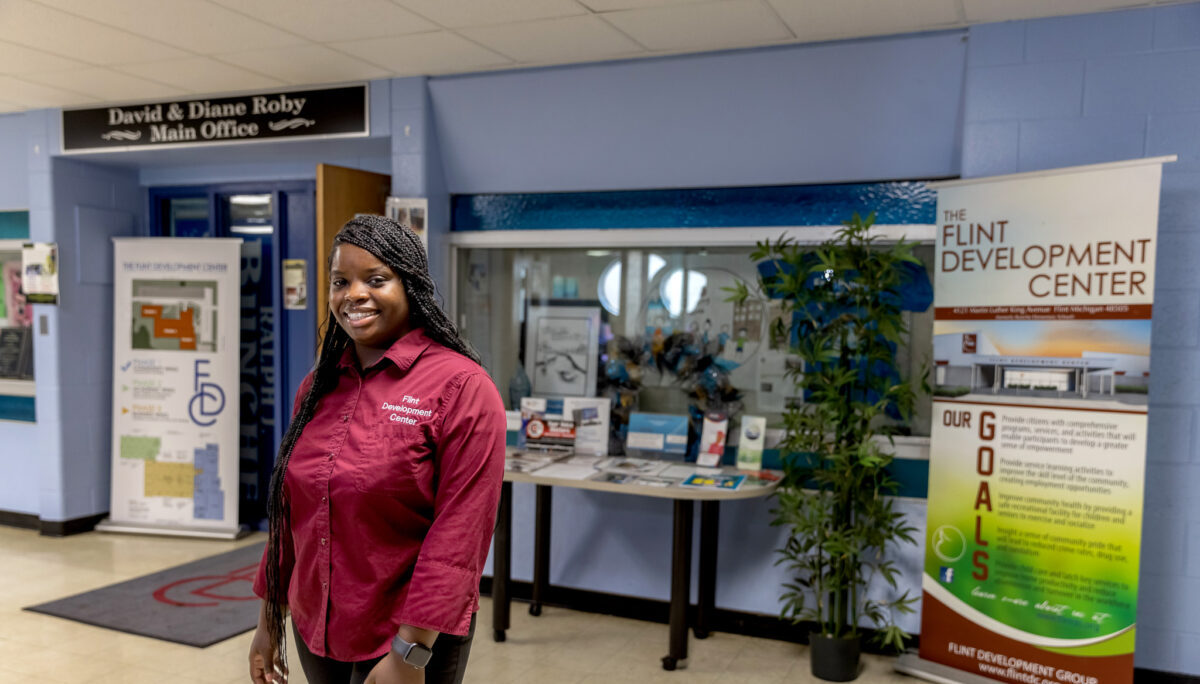 A woman in a maroon shirt stands in a hallway at the Flint Development Center.