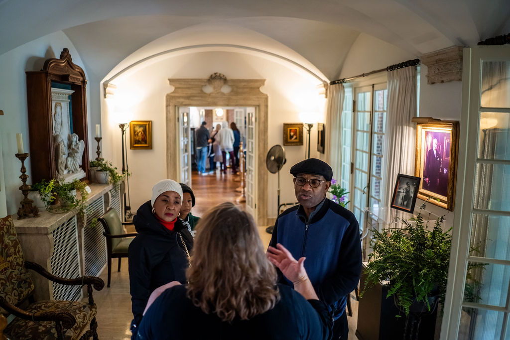 Two visitors listening to an Applewood Tours guide inside a historical building.